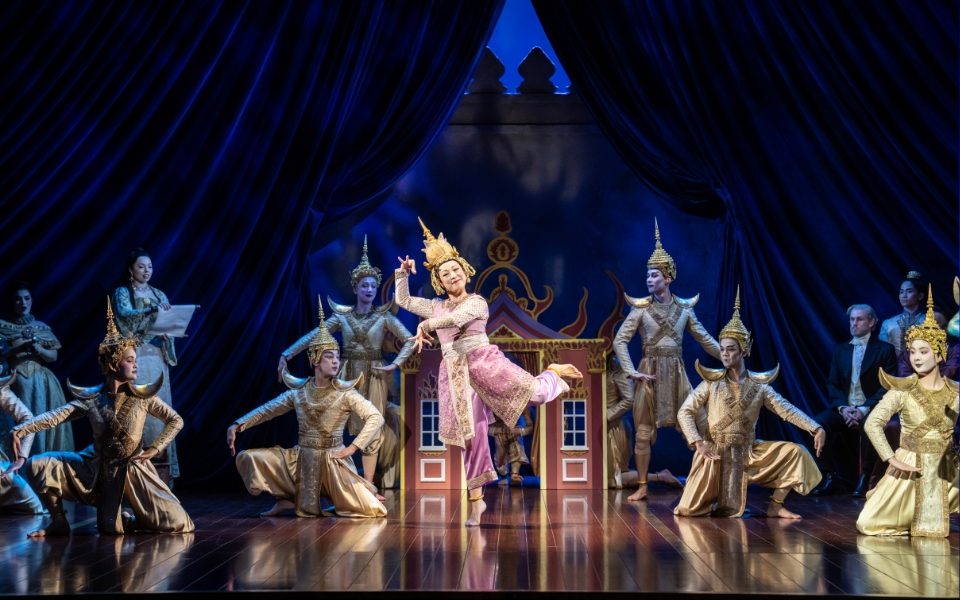 Dancers in The King and I in traditional Thai costumes in formation on the stage.