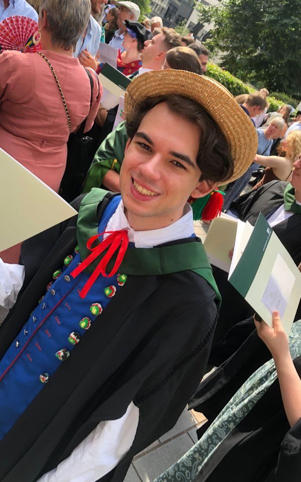 Dominick smiles to camera at a graduation ceremony.