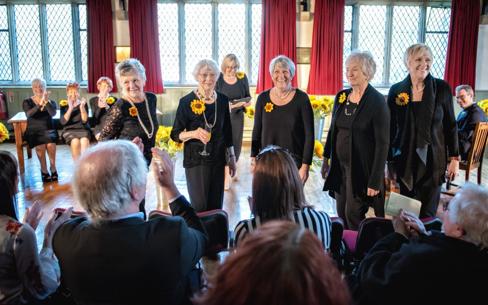 The Calendar Girls are wearing black with their sunflowers.