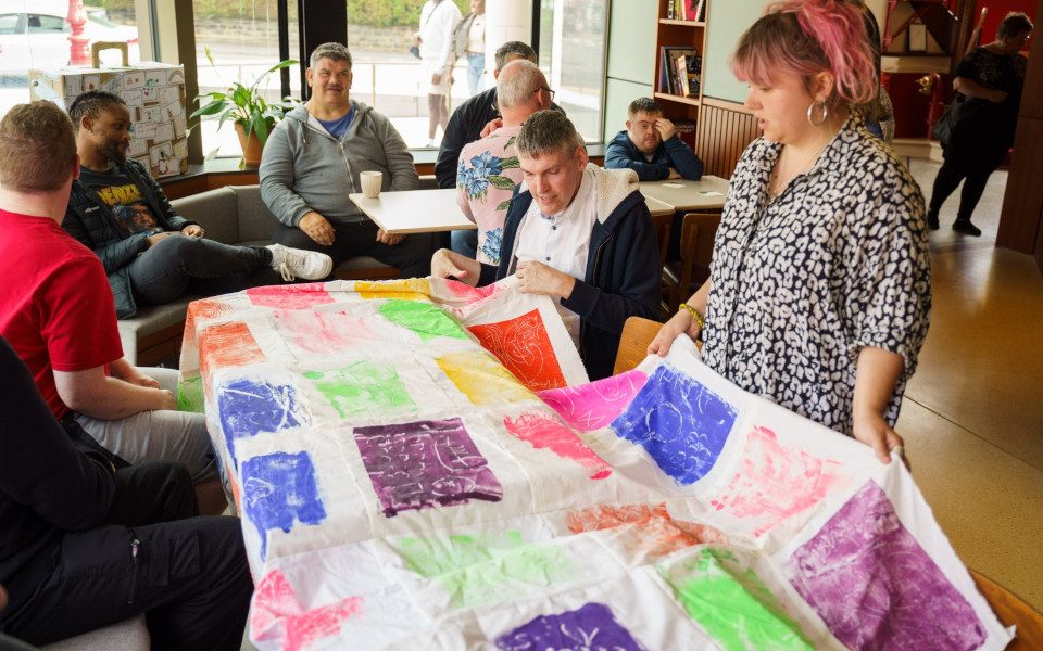 A group of people are looking at a painted sheet.