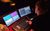 Lighting Training A over the shoulder shot of a student sat at the lighting desk turning dials and pressing buttons in front of two screens.