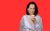 Luisa Omielan Luisa Omielan eating a lemon and pulling a face in front of a red background