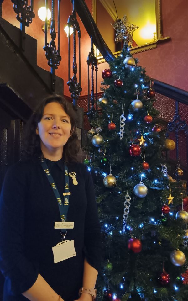 Catherine Hayward stands in front of a large Christmas Tree in the foyer at City Varieties.