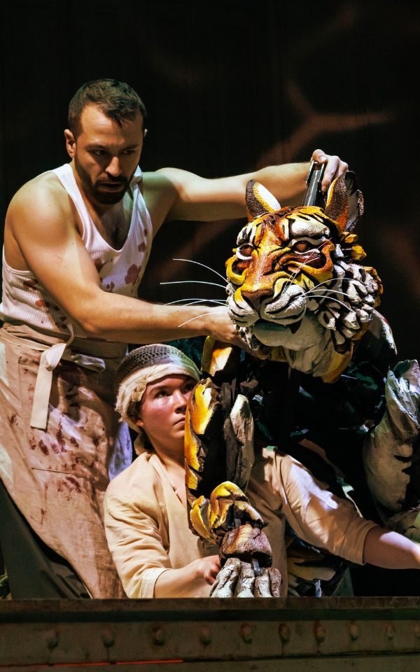 Two puppeteers moving a lifesize tiger puppet