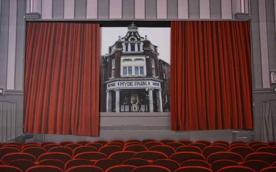Illustration of the Screen 1 auditorium at Hyde Park Picture House with the iconic red curtains open ajar to show an image of the external entrance of The Picture House.