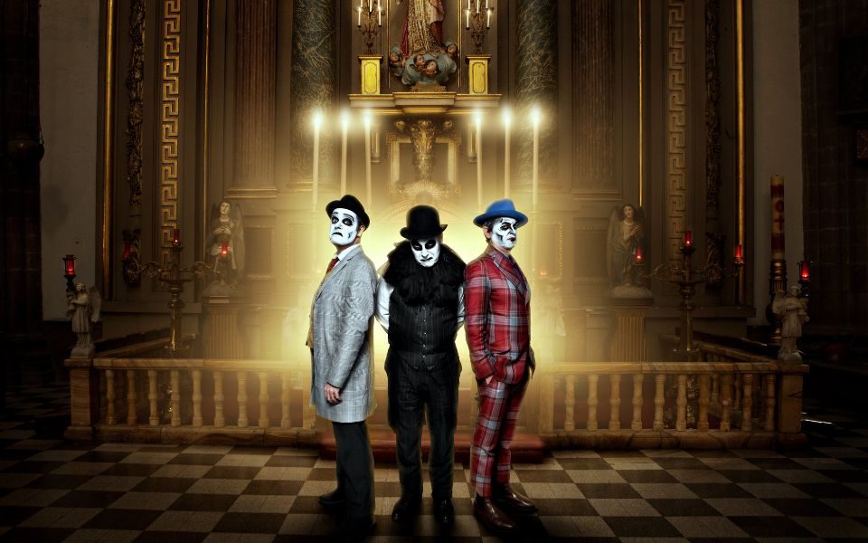 The three Tiger Lillies members stood at the alter of a church wearing fedoras with their faces painted white.