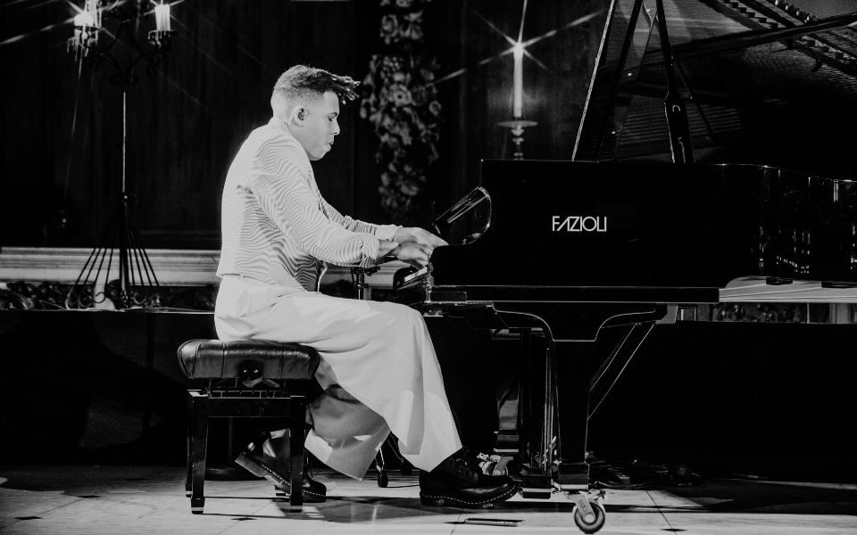 Black and white image of Tokio Myers playing piano on stage.