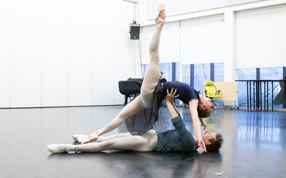 Amber Lewis and Jonathan Hanks rehearsing Romeo & Juliet in the studio. Jonathan holds Amber above him while lying on the floor.