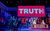 Drop The Dead Donkey The cast of Drop The Dead Donkey on stage with a giant red screen reading Truth News above a news desk.