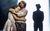 Jaydah Bell-Ricketts as Girl and Carly Mercedes Dyer as Faye Treadwell and Miles Anthony Daley as George Treadwell Jaydah Bell-Ricketts as Girl and Carly Mercedes Dyer as Faye Treadwell hugging on stage with Miles Anthony Daley's silhouette as George Treadwell appearing in the background.