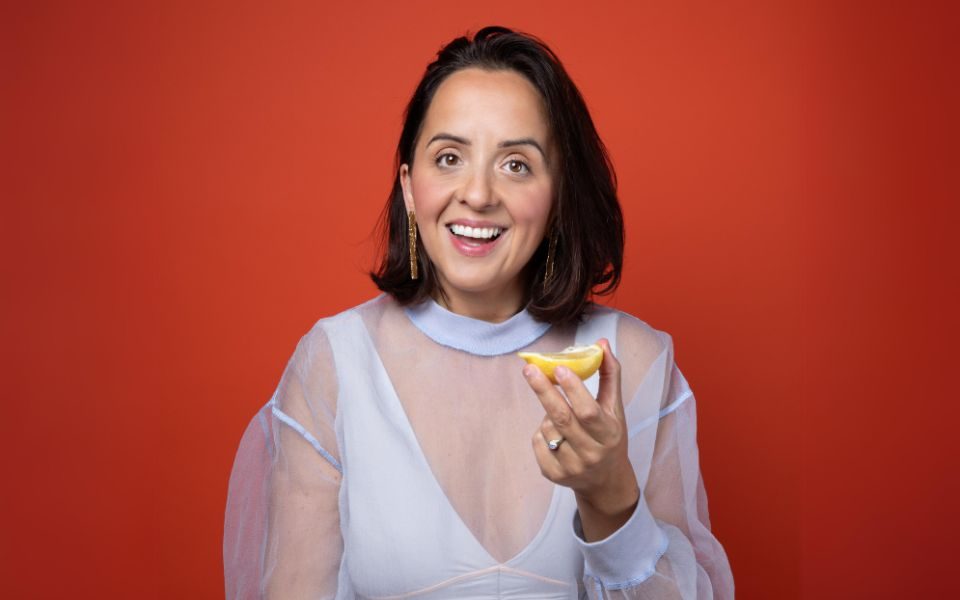 Luisa Omielan smiling at the camera and holding up a lemon.