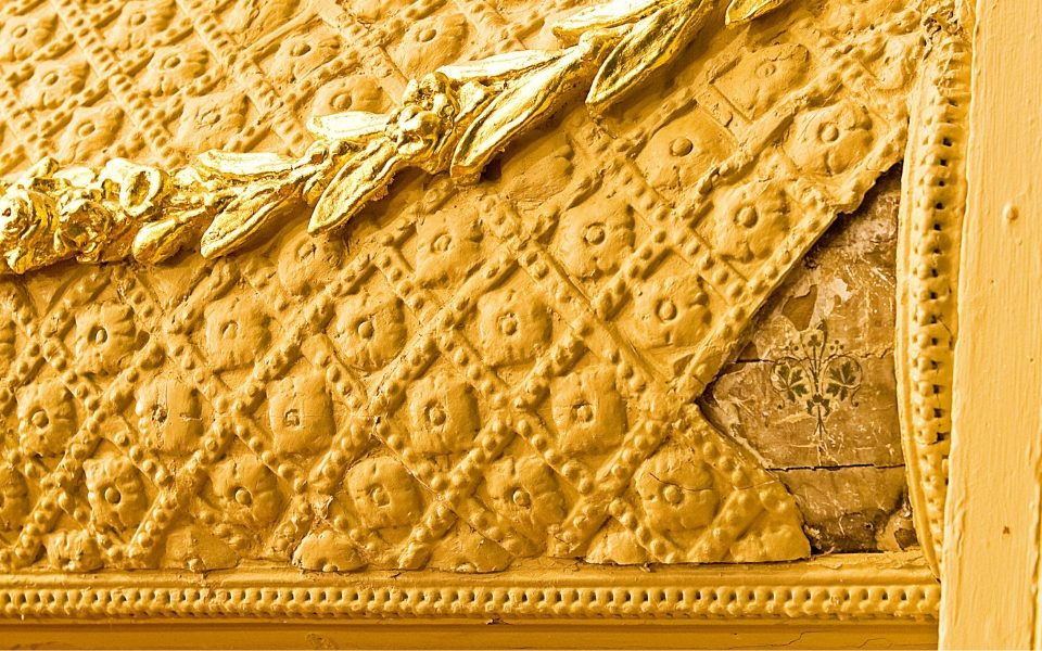 The yellow and gold new plaster work of City Varieties Music Hall is chipped, revealing the Victorian wall decoration beneath.