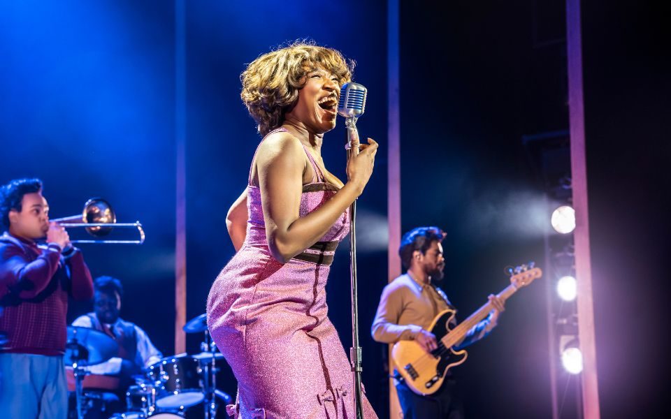 Jochebel Ohene MacCarthy as Tina (Credit: Johan Persson) Jochebel Ohene MacCarthy dressed in pink on stage as Tina with band behind her (Credit: Johan Persson)