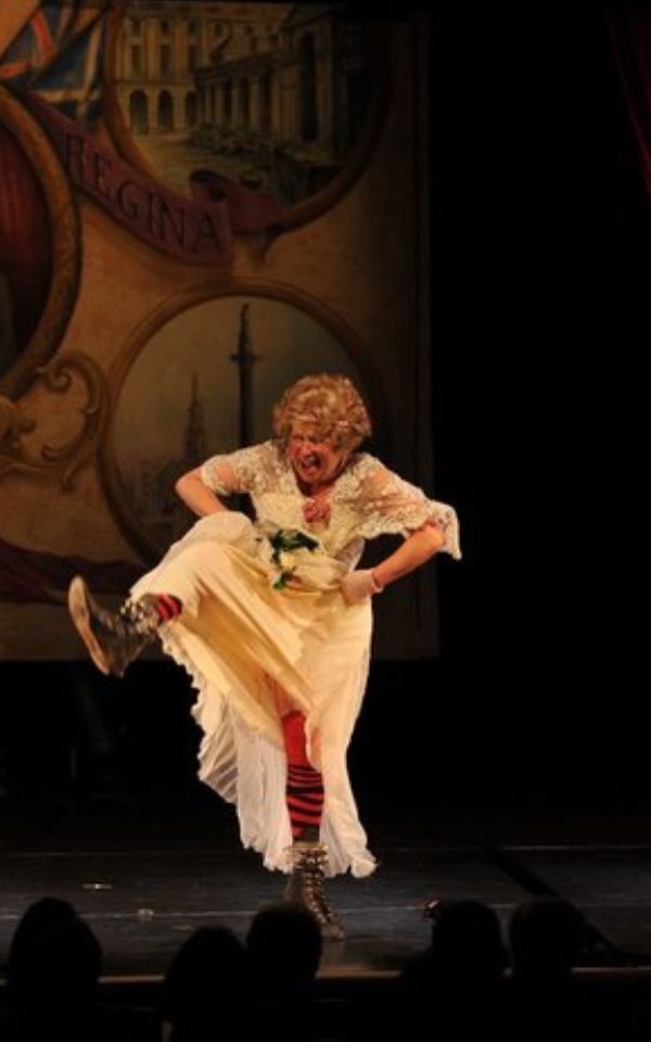 Jan Hunt pulling her dress up to kick out her leg onstage while performing.