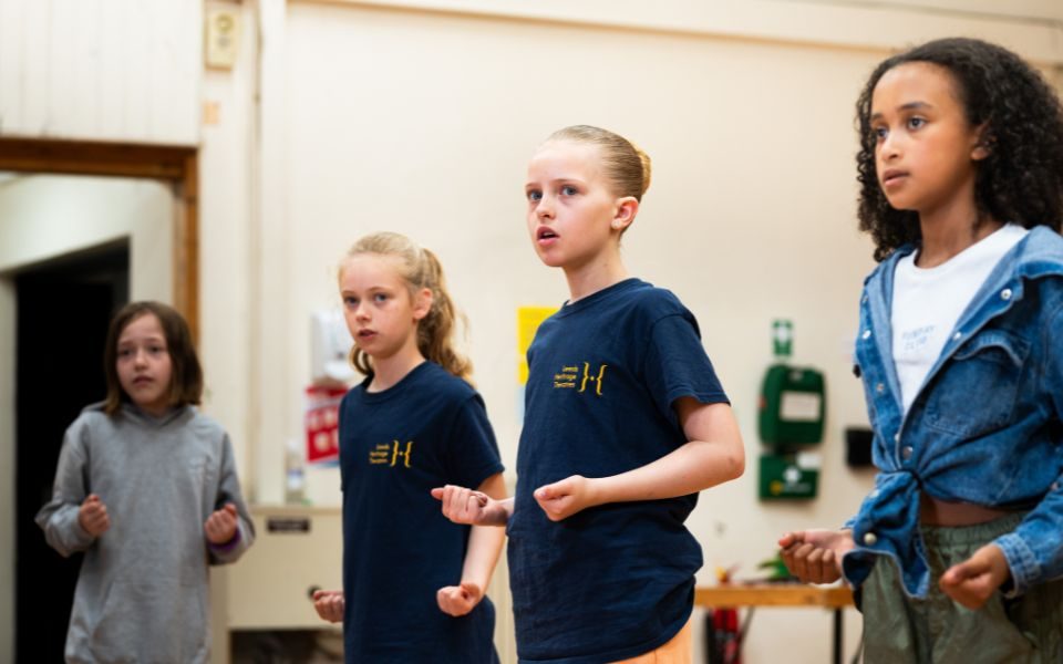 Four children in the studio downstairs in Leeds Grand Theatre. The two girls in the middle are wearing Leeds Heritage Theatres T-shirts.