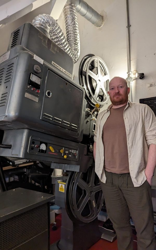Mike Sharples standing next to a film projector.