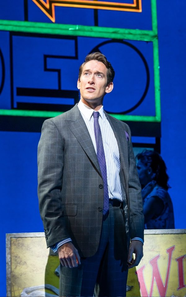 Oliver Savile as Edward Lewis in a suit in Pretty Woman: The Musical.