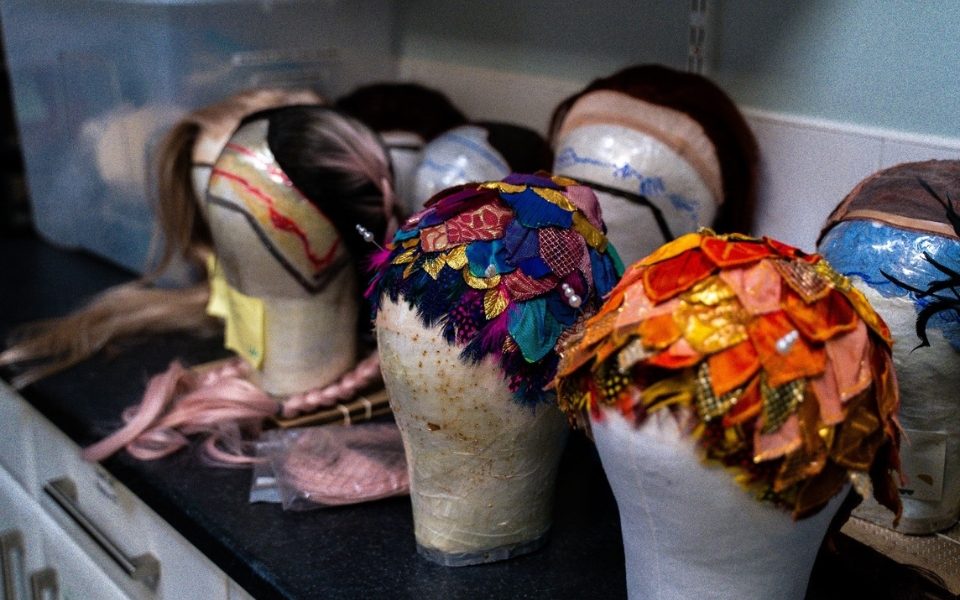 Colourful headdresses on wig stands.