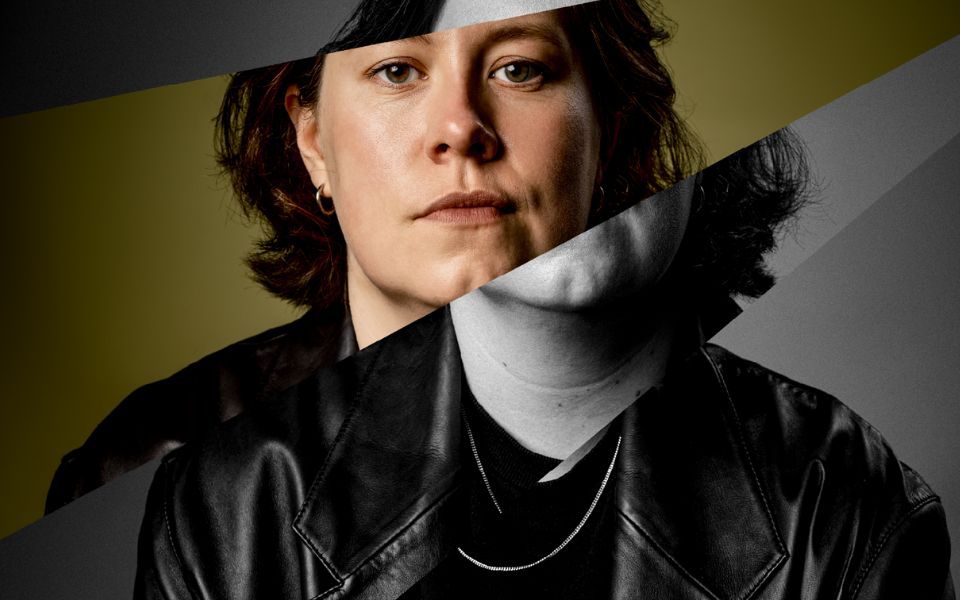 Chloe Petts wearing a black leather jacket looking solemnly at the camera. Image is split up and disjointed with one chunk that includes the majority of her face in colour and the other chunks are in black and white.