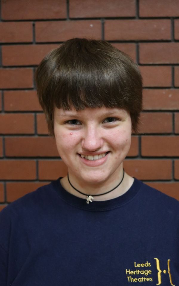 A young actor in their youth theatre t-shirt smiles at the camera for a close-up headshot