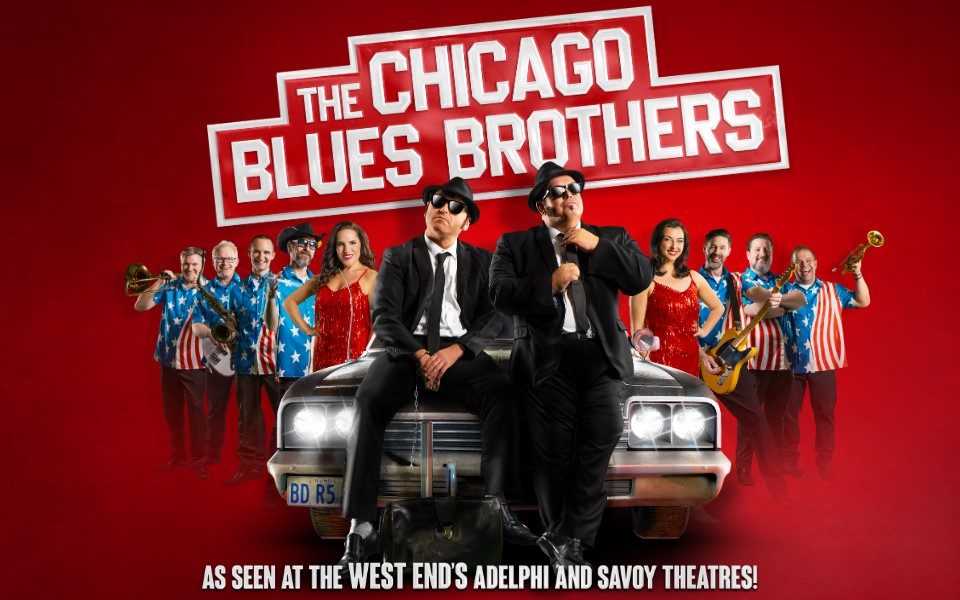 Two men in black suits sat on the bonnet of an old looking car. Behind the car in an arrow-like formation are an all male band with a bassist and horn players wearing American flag shirts. Two women in red fringe dresses appear with the band. Text reads: The Chicago Blues Brothers. As seen at the West End's Adelphi and Savoy Theatres.