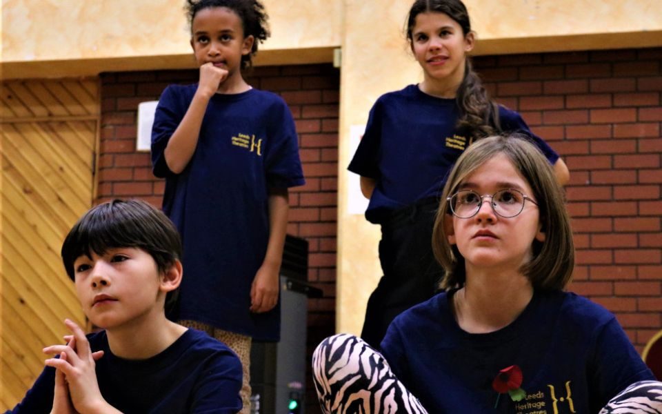 4 young members look on inquisitively. A boy and a girl sat in front of two girls stood behind.