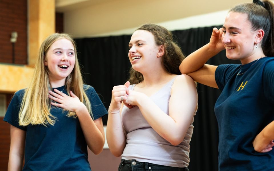 Three actors playing the Ronettes smile during a break in rehearsals.