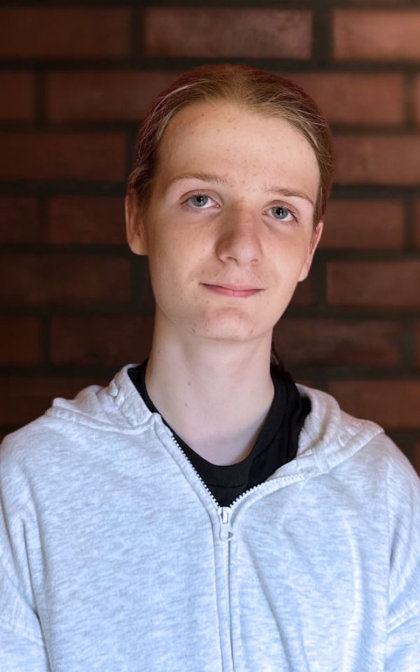 A young actor in a white hoodie smiles at the camera for a headshot.