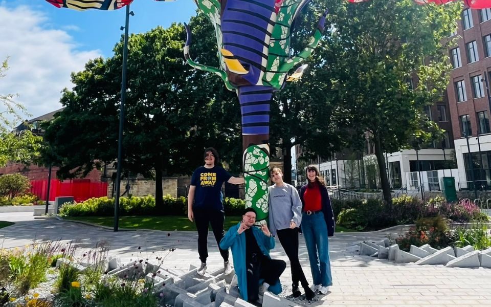 Sarah, Henry, Paul and Aaron stood under a colourful floral art installation