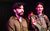 Ashley Pekri in Find a Partner. Ashley looks pensive to camera right. He is dressed in a brown boiler suit. Another person has their eyes closed and right hand raised with their eye closed.