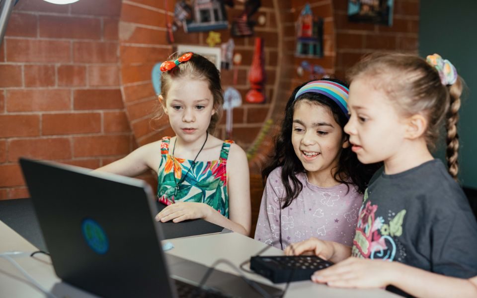 Three young girls stood at a laptop at the LHY Unwrapped: Animation Workshop.