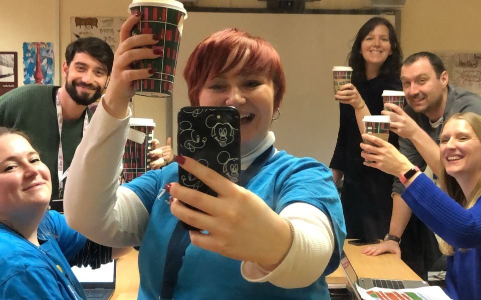 The L&E team raise a coffee during a selfie together.