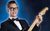 Buddy Holly & The Cricketers Man in tuxedo and bow tie wearing glasses and smiling against a blue background playing a Fender electric guitar.