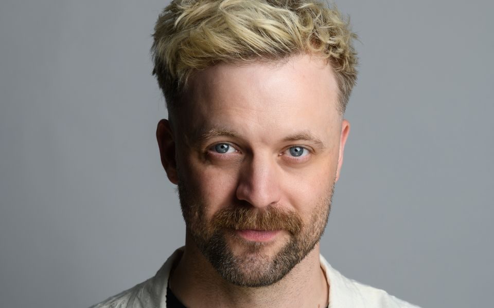 Headshot of Thomas Green against a grey background.