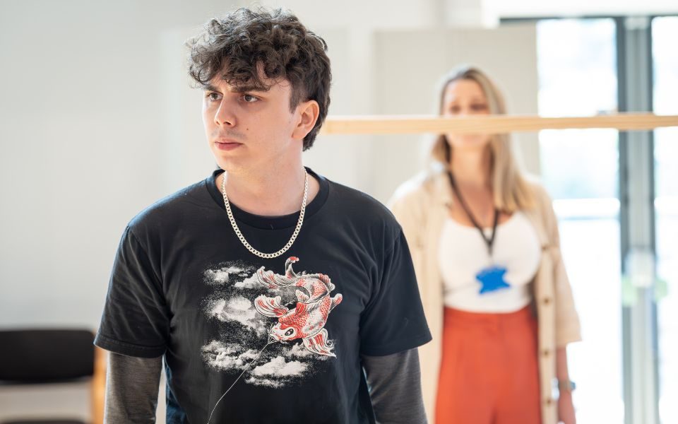 Sonny Monaghan in a black top with Alice Fearn standing behind him in a studio.