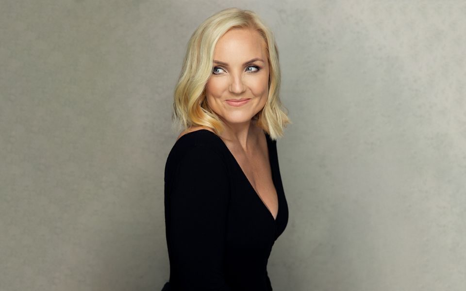 Kerry Ellis wearing a back top looking over her right shoulder.