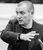 Paul Birch A black and white photo of a Paul Birch in a striped blazer gesticulating towards someone he is directing