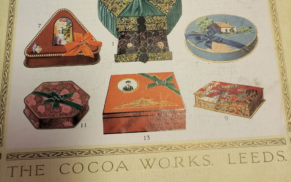 A close up of a colourful chocolate tin flyer depicting decorative tins and emblazoned with the words The Cocoa Works Leeds