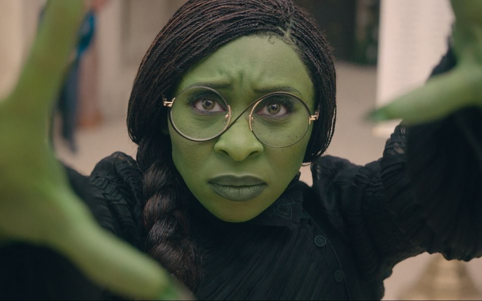 Cynthia Erivo as Elphaba with her iconic green skin, black dress and round glasses.