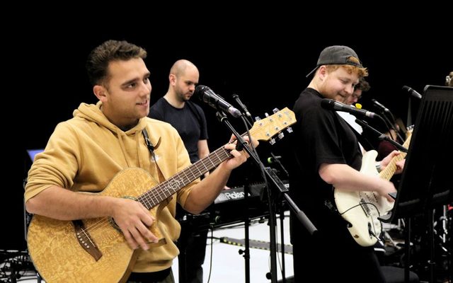 Harry F Brown and Max Bower play guitars as Tom Benjamin plays a keyboard behind them