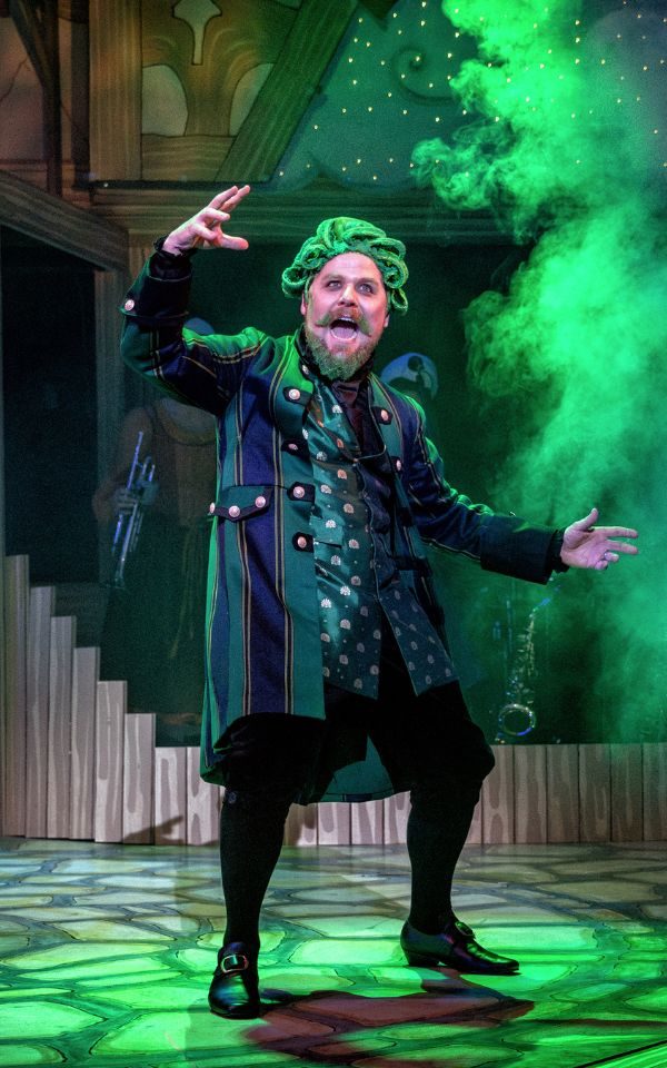 Kenny Davies as panto villain Fleshcreep looking sinister wearing a long green and black coat with a long satin green patterned waistcoat underneath.