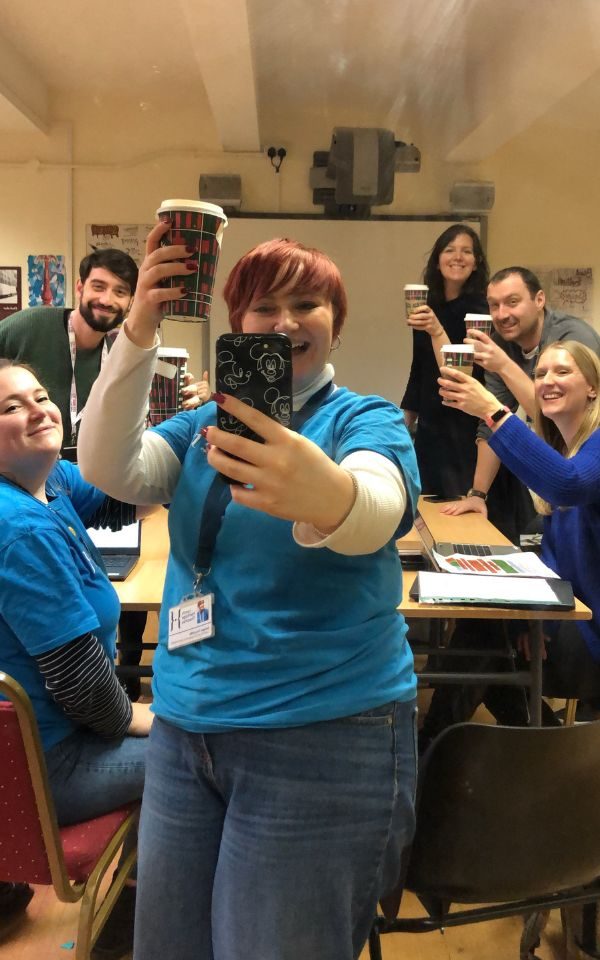 The L&E team raise a coffee during a mirror selfie together