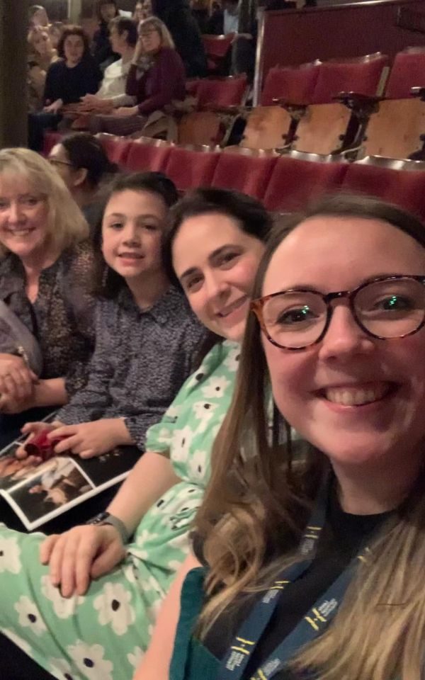 A portrait selfie with four faces in, Sarah, her sister in law, her niece and her mum, and with theatre seats at the Grand in the background