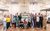 Calamity Jane Cast The cast of Calamity Jane grouped together with a poster for the show smiling at the camera in the rehearsal studio.