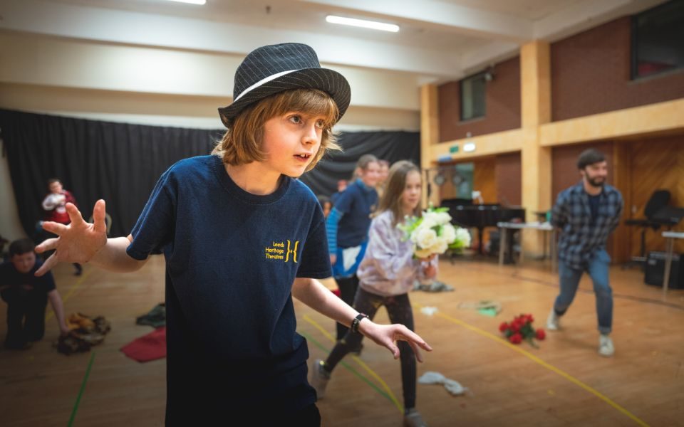 A child in a navy blue LHT top posing like a statue and wearing a hat.