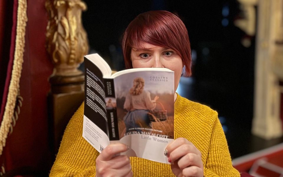 Imogen gasping as she reads Little Women in the auditorium at City Varieties Music Hall