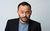 Geoff Norcott Geoff Norcott wearing a pale blue tshirt under a black suit jacket looking straight-faced at the camera.