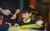 Pupil with yellow paper. Credit Ollie Jenkins A primary schoolchild sits smiling at a desk with a piece of yellow paper