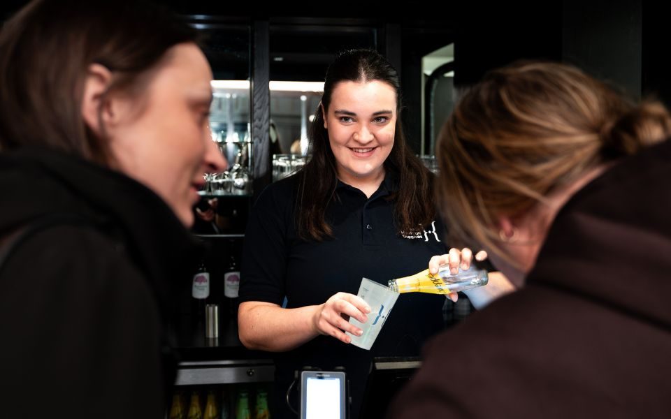 A staff member pouring a drink for a customer behind the bar in Howard Grand Hall.