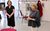 By Royal Appointment Caroline Quentin in the background with her hands folded watching Anne Reid in the foreground clasping her hands. They stand in a rehearsal studio with red chairs dotted around.